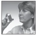 A woman holding an inhaler near her face for the treatment of respiratory problems, looking at it attentively