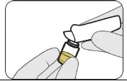 Gloved hands holding a small glass vial with yellow liquid while inserting a white medical device onto the container neck