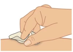 Una mano applica delicatamente un cerotto o una medicazione adesiva sulla superficie della pelle di un braccio o di una gamba