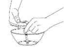 Two hands carefully pouring the contents of a vial into a small bowl containing liquid