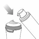 A gray arrow indicates the movement of a cylindrical container being pressed downward onto a cap with a small amount of cream