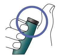 One hand holding a green cylindrical medical device with a gray cap highlighted by an upper blue circle