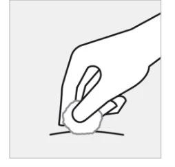 A hand holding a round tablet and gently placing it on a flat surface or on the skin