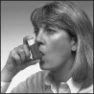 A woman with light-colored hair holds a small vial close to her mouth, ready to take its contents, in a black and white photo
