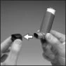 Two hands showing how to insert a square black component into a cylindrical device, indicated by a white directional arrow
