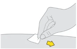A hand gently peels off a small white paper strip from a flat surface, indicated by a yellow arrow pointing to the right