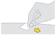 A hand holds a small white paper strip on a gray surface with a yellow arrow pointing to the right