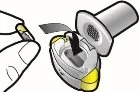 A hand removes the white protective cap from a yellow medical injection device with yellow details and an internal black insert