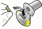 A hand holds a white and yellow capsule while inserting it into a device
