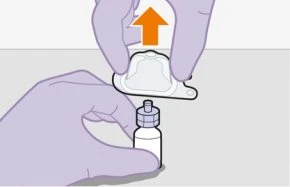 Purple-gloved hands lifting a white protective cap from a small medicine vial with an orange arrow pointing upward