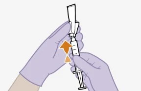 Two gloved hands holding a syringe while an orange arrow indicates movement toward