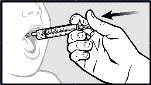 A hand holds a needle-free syringe and gently inserts it into a child's mouth to administer liquid medication