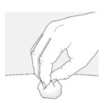 A hand holding between thumb and index finger a small, round, transparent object on a flat surface