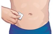 A hand applying a small white adhesive bandage to the skin of the abdomen