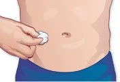 A hand holding a white cotton ball over the injection site on the abdomen