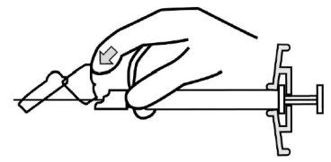 A hand holding a horizontal syringe, pressing downward with the thumb on the top part to activate the injection mechanism