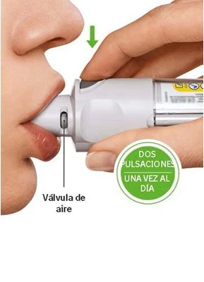 A hand holding a white medical device against a person's lips, with a green arrow and the text 'Válvula de aire'
