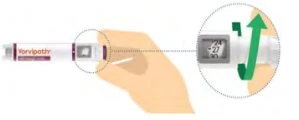 A hand holding a Vorvypath medical device with a magnified inset showing a digital display and a double-pointed green arrow
