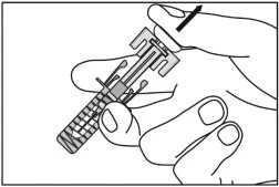 One hand holding a cylindrical transparent medical device while the thumb presses downward on the top to activate it