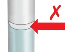 Medical illustration of a cylindrical device with a red arrow pointing to the junction between the upper white and lower blue part, with a red cross above