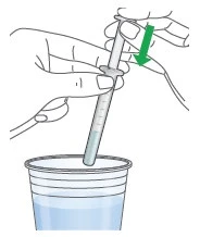 Two hands hold a syringe with liquid while the tip is immersed in a transparent container filled with liquid