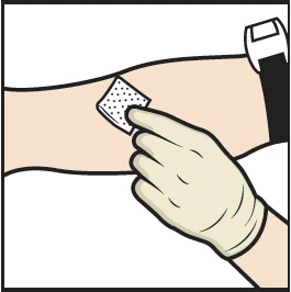 A gloved hand applies a square perforated patch to the skin of an outstretched arm, with a medical device visible in the upper right corner