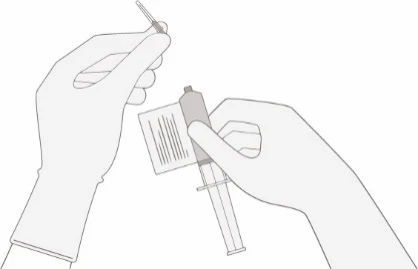 Две руки в перчатках готовят шприц, одна из которых снимает защитный колпачок с