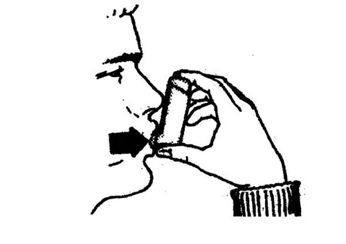 Dibujo en blanco y negro de un perfil humano que sostiene un inhalador cerca de la boca con una flecha negra que indica la dirección del flujo del medicamento