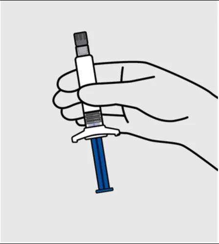 Una mano sostiene verticalmente una jeringa blanca con un émbolo azul y una parte superior gris sobre fondo neutro