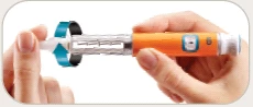 Two hands holding horizontally a medical injection pen with orange body and transparent reservoir showing the letter 'l'