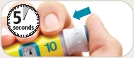 Two fingers pressing the white cap of a yellow medical device with number 10 and a