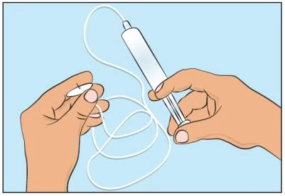 Dos manos sostienen un dispositivo médico cilíndrico blanco conectado a un tubo flexible y delgado sobre fondo azul