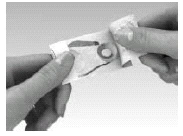 Two hands carefully open an aluminum foil pouch to remove the drug contents against a light, neutral background