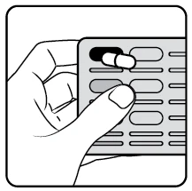 A hand holding a pill blister pack, pressing the thumb on a white capsule to push it out from the grey compartmented packaging