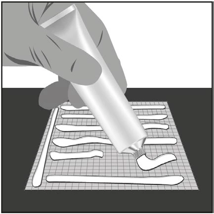 A hand squeezing a tube of cream to apply horizontal stripes of white product onto a surface with a square grid pattern