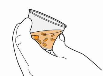 Two hands hold a transparent glass containing an amber-colored liquid with both hands