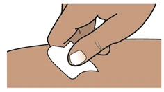A hand with dark skin pressing a white cotton swab onto the skin surface of an arm or leg