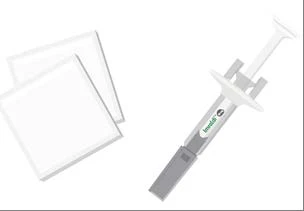 Jeringa gris y blanca con etiqueta verde junto a dos hojas rectangulares blancas sobre fondo neutro