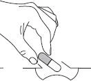 A hand holds a gray and white pharmaceutical capsule above a flat surface with a small central slit