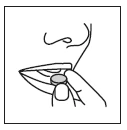 A hand holds a round, flat tablet near the open mouth of a person for