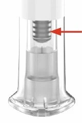 Detalle de un dispositivo médico transparente con componentes internos metálicos y una flecha roja que apunta hacia la parte superior del cilindro