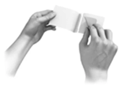 Two hands hold and open a folded leaflet against a neutral white background