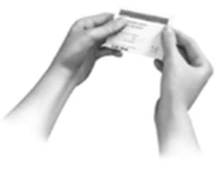Two hands hold and open a small white rectangular information leaflet with black text against a neutral background
