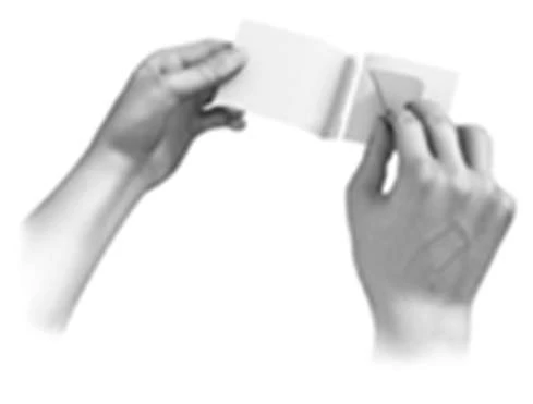 Two hands hold and carefully open a small white rectangular pouch or envelope to remove its contents