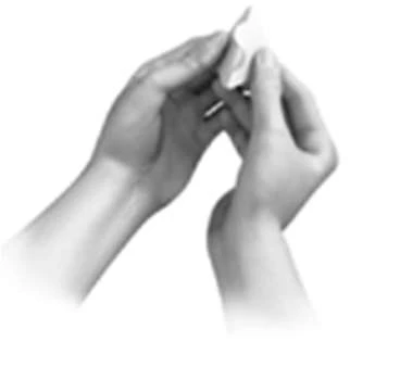 Two hands hold and carefully open a small medicine package or pouch against a white background