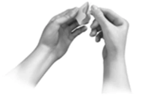 Two hands hold and gently separate a small white object or component of a medical device against a neutral background