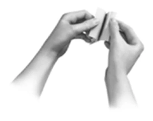 Two hands hold and open a small white rectangular container or package against a neutral background