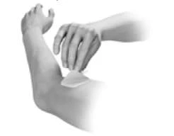 A hand gently presses a patch or dressing on the inner elbow of a bent arm