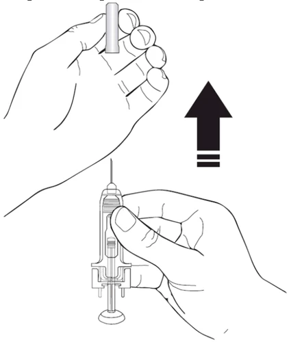 A hand vertically lifting a protective cap off a syringe with the needle pointing upward