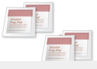 Четыре квадратные упаковки салфеток, пропитанных спиртом, называемых Alcohol Prep Pad, с белыми этикетками и верхней бледно-розовой полосой